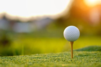 article image - Golf ball on tee in the evening golf course with sunshine background.